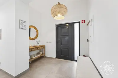 a kitchen with white walls and black cabinets and a table at Villa Benjamin - Vale do Lobo in Vale do Lobo