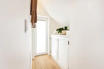 a white hallway with a door and a plant on a cabinet at BLQ Charneco 1BDR in Boliqueime by LovelyStay in Boliqueime