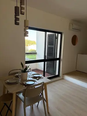 a dining table and chairs in a room with a large window at Cozy and chic apartment in Albufeira