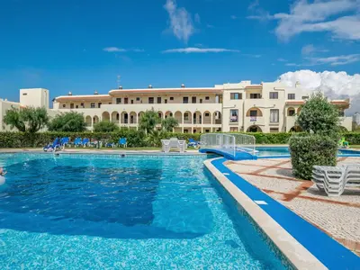 a swimming pool with a building in the background at Akisol Albufeira Eris in Albufeira