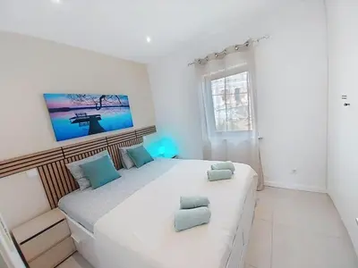 a white bedroom with a large bed with blue pillows at Panorama Old Town sea view Albufeira in Albufeira