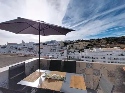 a table with an umbrella on top of a building at Panorama Old Town sea view Albufeira in Albufeira