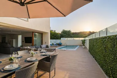 a kitchen and dining room with a wooden table and chairs at Two Luxury Villas with Private Pools near Old Town Albufeira in Albufeira