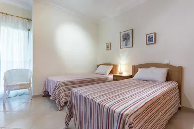 a bedroom with two beds and a chair and a window at vista golf in Quarteira