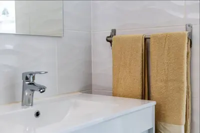 a bathroom with a sink and a mirror and towels at Blife Lucelya private rooms at Faro beach in Faro