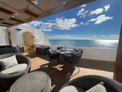 a patio with a table and chairs and the ocean at casa do cesar in Albufeira