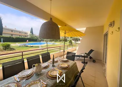 a dining room with a table and a view of a pool at MyStay - Farol Moura in Quarteira