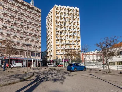 a blue car parked in front of a large building at Akisol Faro Virtuous in Faro