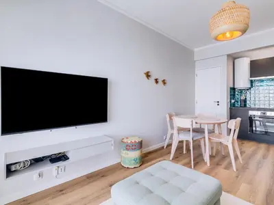 a living room with a tv and a table at Apartamento Vida Pura com 2 quartos e vista mar in Quarteira