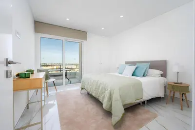 a white bedroom with a bed and a large window at Talia Lux - two-bedroom luxury apartment by HD in Vilamoura