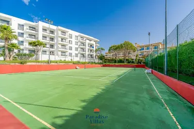 a tennis court in front of a large apartment building at Two Bedroom Apartment with Sea Views in Albufeira in Albufeira