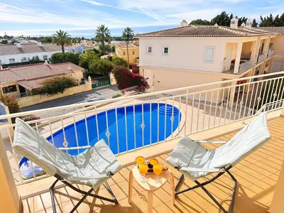 a balcony with two chairs and a table and a pool at Balaia Maggs House Pool & Ocean view by BeCherish in Albufeira