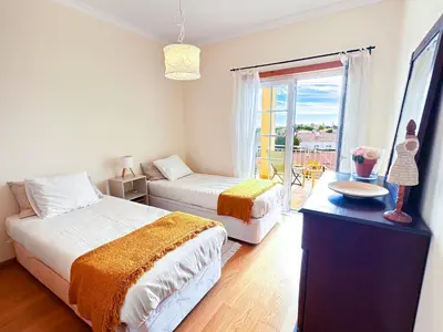 a bedroom with two beds and a table and a window at Balaia Maggs House Pool & Ocean view by BeCherish in Albufeira