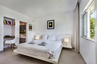 a white bedroom with a white bed and a window at Casa Florida in Almancil