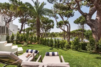 a lawn with chaise lounge chairs and palm trees at Casa Florida in Almancil