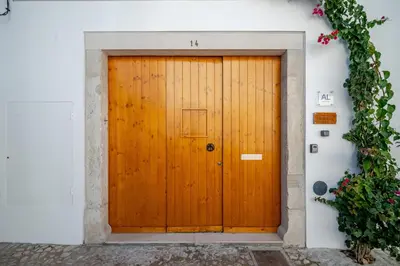a wooden door in a white wall with a ivy at The Warehouse - Industrial Loft in Faro