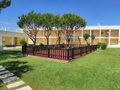 a fence in front of a building with a playground at ABF62 confortavel T2 a 2,5km praia Gale in Galé