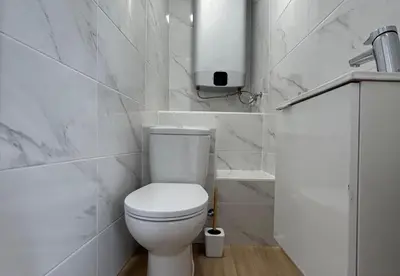 a white bathroom with a toilet and a sink at Playa Vista guest house in Albufeira