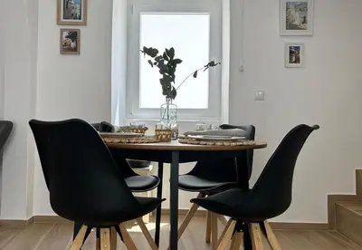 a dining room table with black chairs and a vase of flowers at Playa Vista guest house in Albufeira