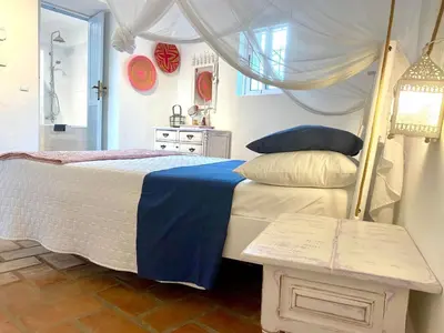 a bedroom with a bed with a blue blanket and a table at Holiday Home Vila Verão Nur für Erwachsene by Interhome in Santa Bárbara de Nexe