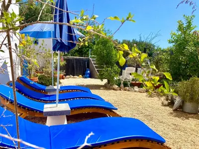 a row of blue lounge chairs with an umbrella at Holiday Home Vila Primaveira - Nur für Erwachsene by Interhome in Santa Bárbara de Nexe