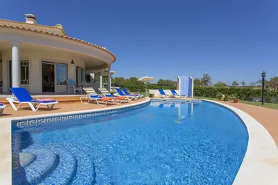 a swimming pool with chairs and a house at Villa Anthony by Villa Plus in Terras Novas