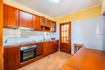 a kitchen with wooden cabinets and a table in it at Villa Carela in Albufeira