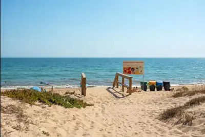 a beach with a sign in the sand and the ocean at Blife Petrya private rooms at Faro beach in Faro