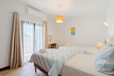 a bedroom with two beds and a window at Villa Navegante com Piscina Privada em Vilamoura in Quarteira