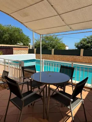 a table and chairs under an umbrella next to a swimming pool at Villa Sun & Shine in Faro