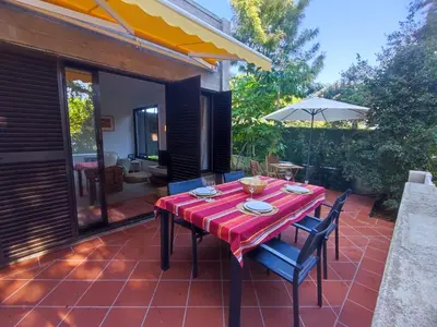 a patio with a table and chairs and an umbrella at T2 Apartment with private garden in the Balaia Apartments, Albufeira, Algarve in Atalaia