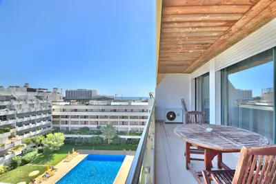a balcony with a table and a swimming pool at Vilamoura Aquamar in Quarteira