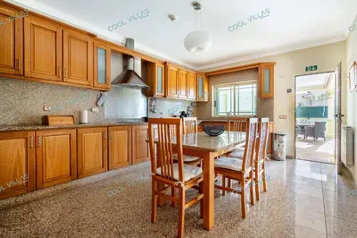 a kitchen with wooden cabinets and a wooden table and chairs at Villa Cibel - Beach & Golf 10pax in Guia