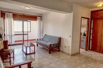 a living room with a chair and a table at Charming Getaway Apartment in Quarteira in Quarteira