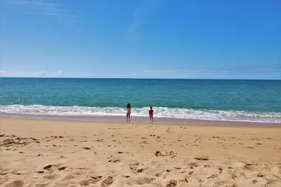 two people standing on a beach near the ocean at Charming Getaway Apartment in Quarteira in Quarteira