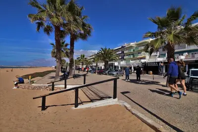 a group of people walking on a beach with palm trees at Charming Getaway Apartment in Quarteira in Quarteira