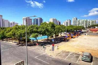 a street with a parking lot with trees and buildings at Charming Getaway Apartment in Quarteira in Quarteira