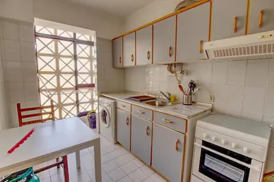 a kitchen with white cabinets and a sink and a stove at Charming Getaway Apartment in Quarteira in Quarteira