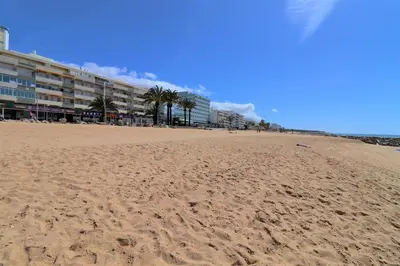 a sandy beach with buildings and palm trees on it at Charming Getaway Apartment in Quarteira in Quarteira