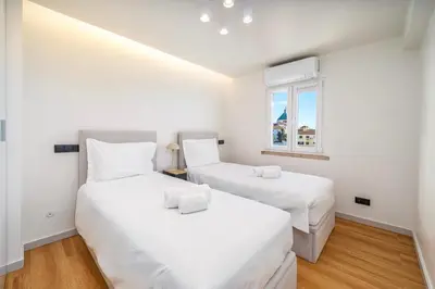 two beds in a white room with a window at Marina Búzios Vilamoura Central 2-Bedroom Apartments in Vilamoura