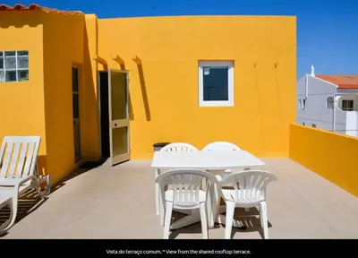 a patio with a white table and chairs on a yellow building at Blife Mariangya private rooms at Faro beach in Faro