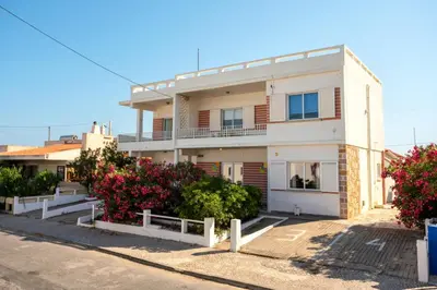 a white building with flowers in front of it at Blife Sonya private rooms at Faro beach in Faro