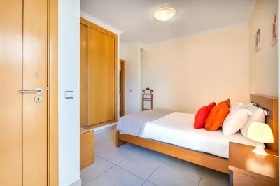 a bedroom with a bed with orange and white pillows at Bright 2BR with Pool near Beach by LovelyStay in Albufeira