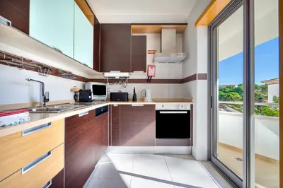 a kitchen with wooden cabinets and a large window at Bright 2BR with Pool near Beach by LovelyStay in Albufeira