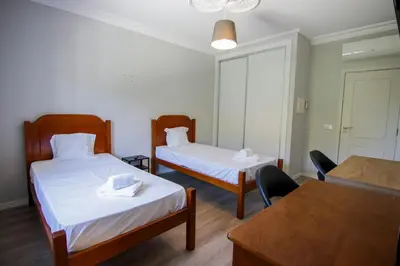 a room with two beds and a table and chairs at QUANICE - Relaxing Guest House in Faro in Faro