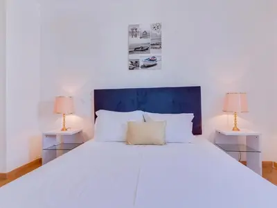 a bedroom with a large white bed with two lamps at Colina Beach Holidays, 2 bdr Apartment Quarteira in Quarteira