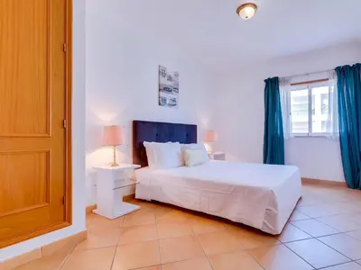 a bedroom with a white bed and a window at Colina Beach Holidays, 2 bdr Apartment Quarteira in Quarteira