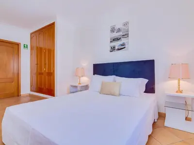 a bedroom with a large white bed and two lamps at Colina Beach Holidays, 2 bdr Apartment Quarteira in Quarteira
