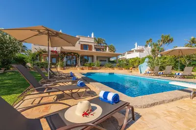 a pool with chairs and umbrellas next to a house at Casa da Praia in Galé