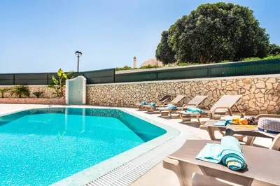 a swimming pool with lounge chairs next to a wall at Villa Gale Coast in Guia
